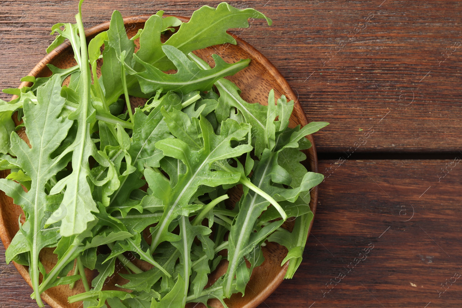 Photo of Fresh green arugula leaves on wooden table, top view. Space for text