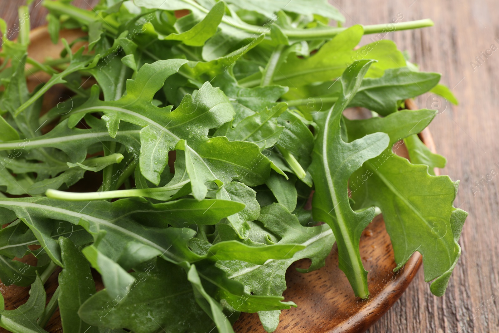 Photo of Fresh green arugula leaves on wooden table, closeup