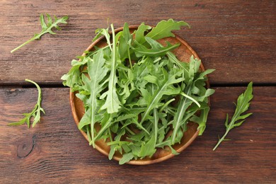 Photo of Fresh green arugula leaves on wooden table, top view