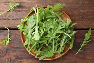 Photo of Fresh green arugula leaves on wooden table, top view