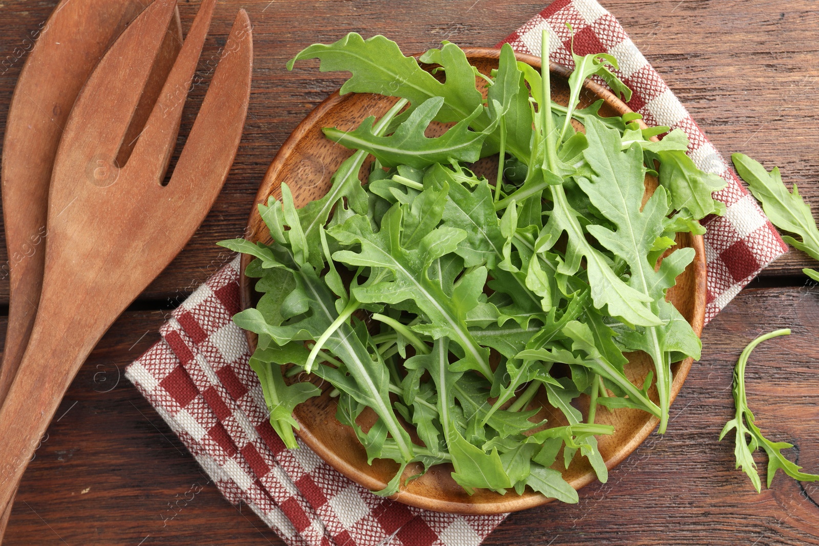 Photo of Fresh green arugula leaves and cutlery on wooden table, flat lay