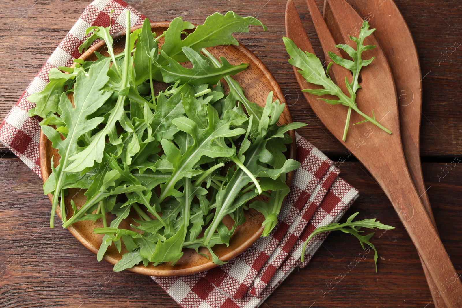 Photo of Fresh green arugula leaves and cutlery on wooden table, flat lay