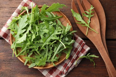 Photo of Fresh green arugula leaves and cutlery on wooden table, flat lay