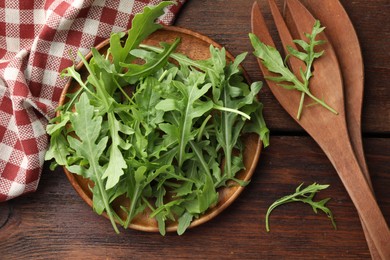 Photo of Fresh green arugula leaves and cutlery on wooden table, flat lay