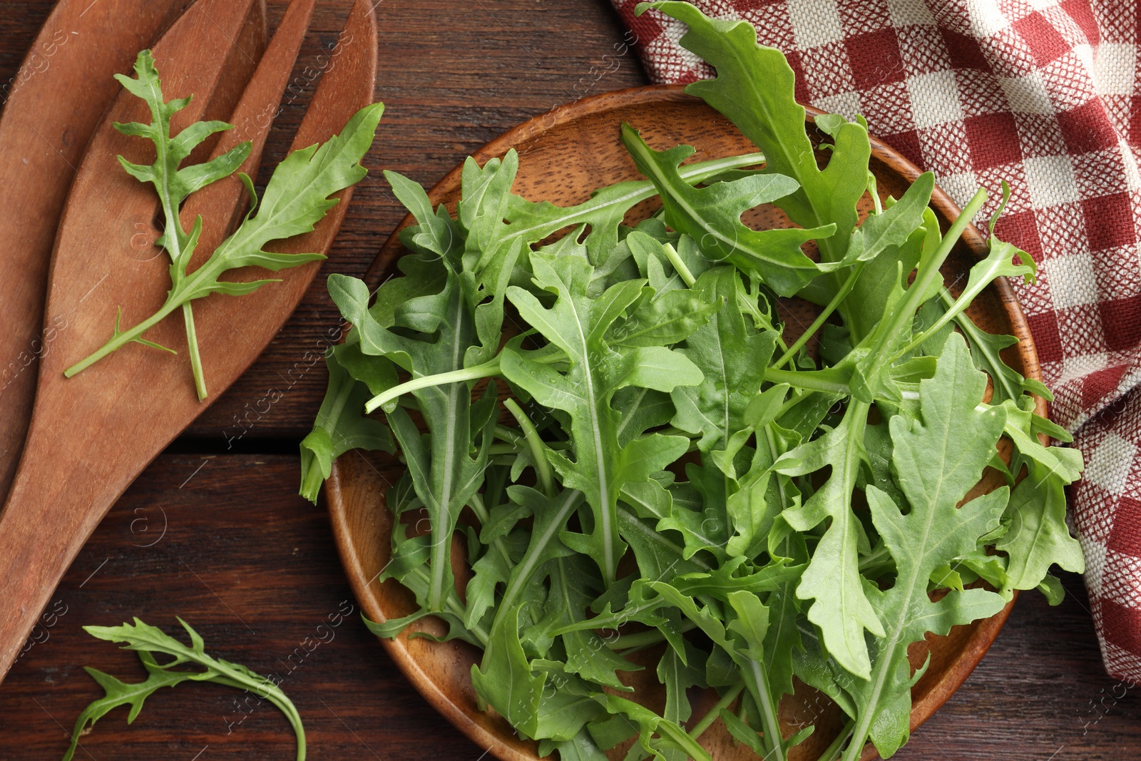 Photo of Fresh green arugula leaves and cutlery on wooden table, flat lay