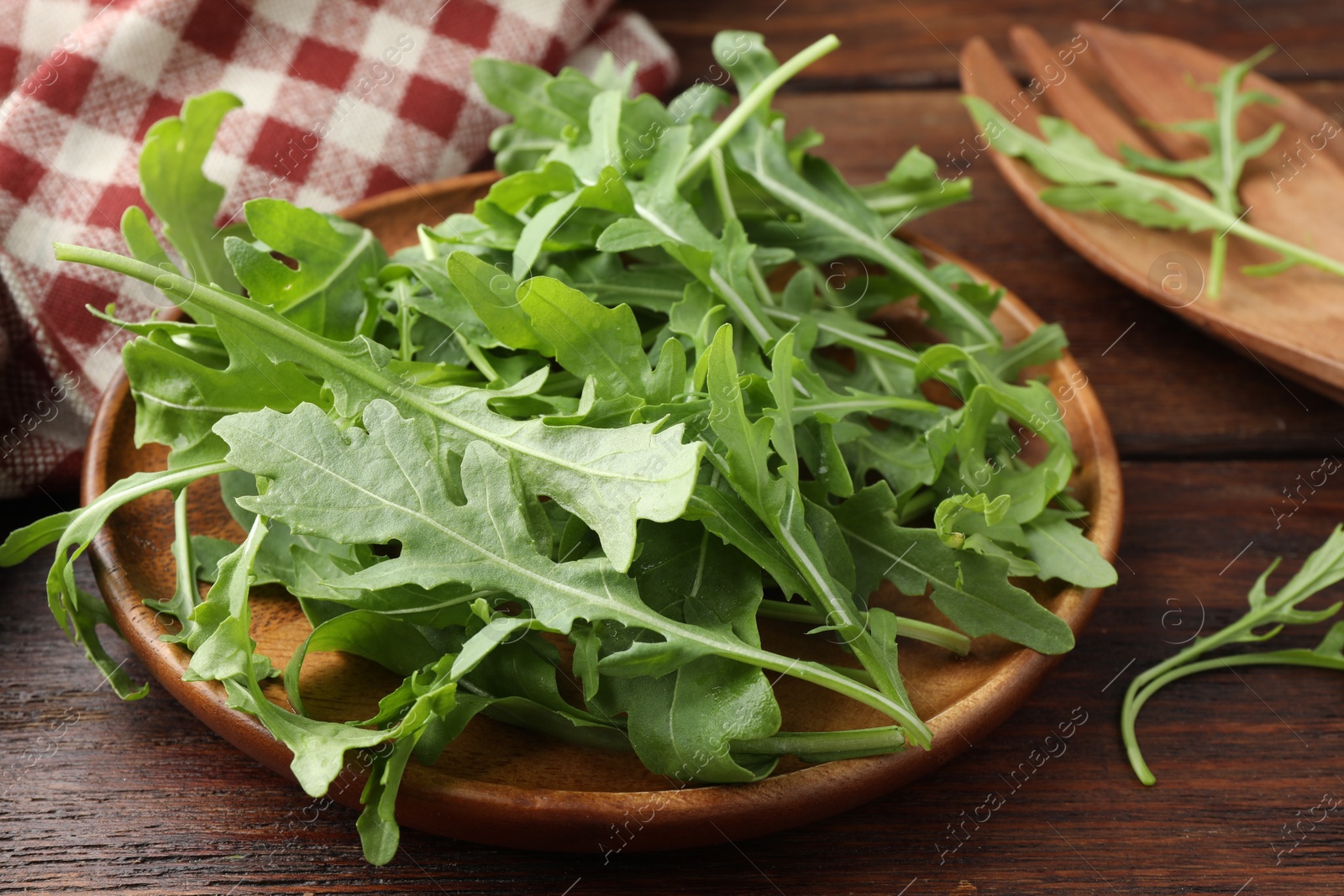 Photo of Fresh green arugula leaves on wooden table, closeup