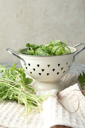 Photo of Fresh green arugula leaves in colander on table