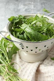 Photo of Fresh green arugula leaves in colander on table