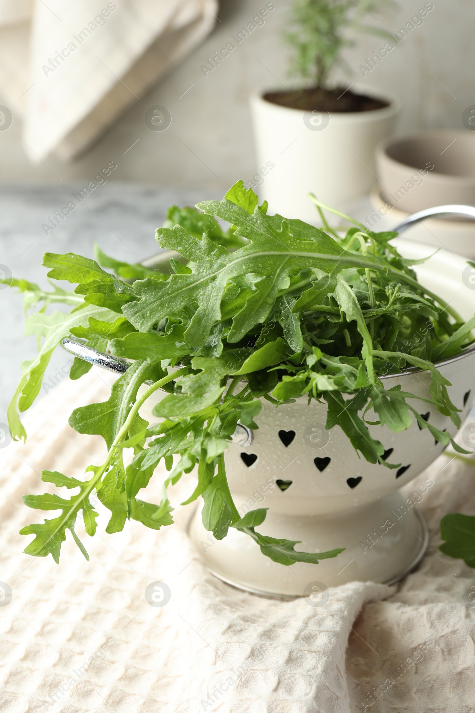 Photo of Fresh green arugula leaves in colander on table