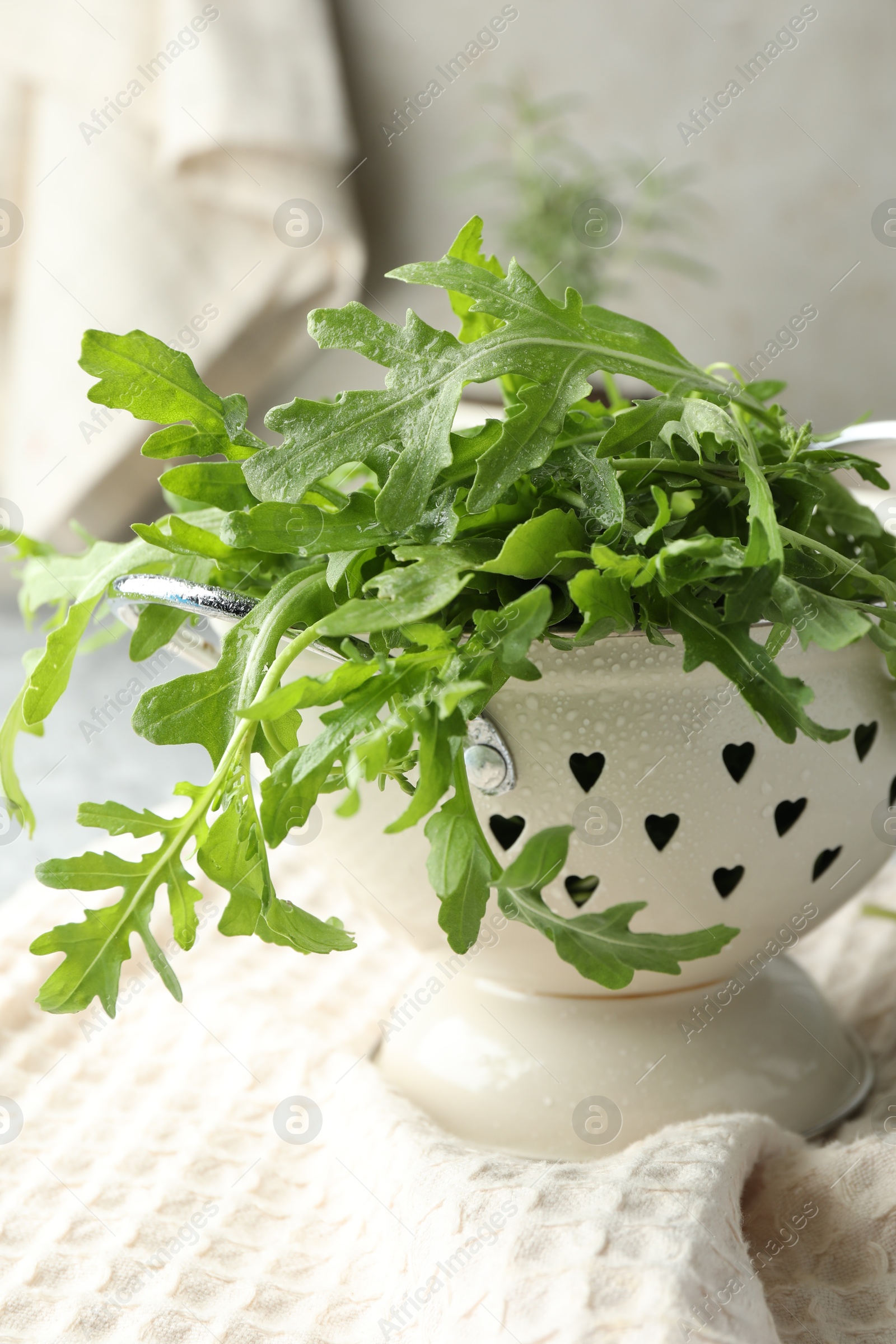 Photo of Fresh green arugula leaves in colander on table