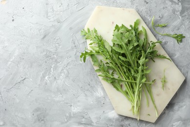 Photo of Fresh green arugula leaves on grey textured table, top view. Space for text