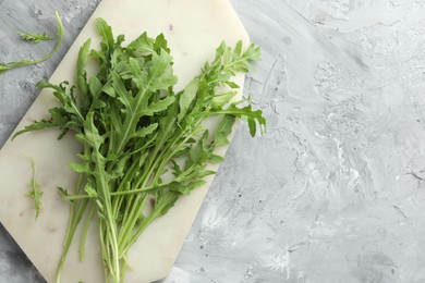 Photo of Fresh green arugula leaves on grey textured table, top view. Space for text