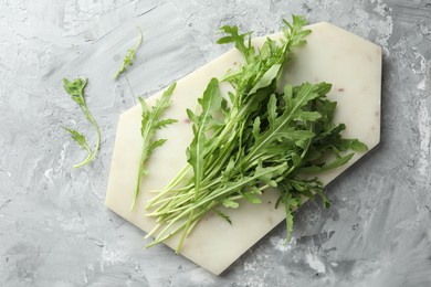 Photo of Fresh green arugula leaves on grey textured table, top view