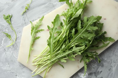 Photo of Fresh green arugula leaves on grey textured table, top view