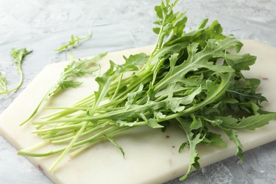 Photo of Fresh green arugula leaves on grey textured table, closeup