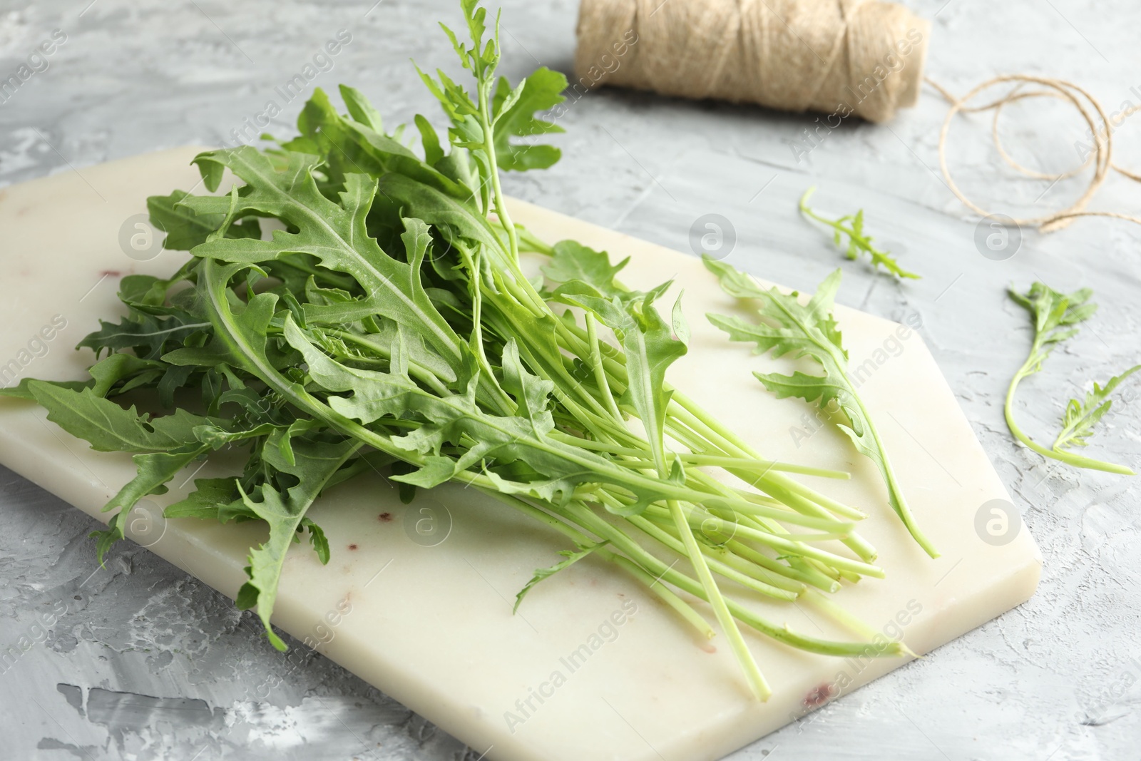 Photo of Fresh green arugula leaves on grey textured table