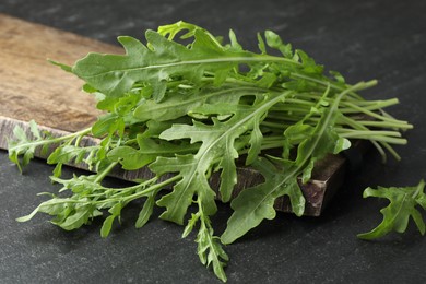 Photo of Fresh green arugula leaves on grey textured table, closeup