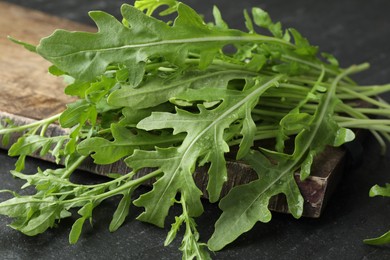 Photo of Fresh green arugula leaves on grey textured table, closeup