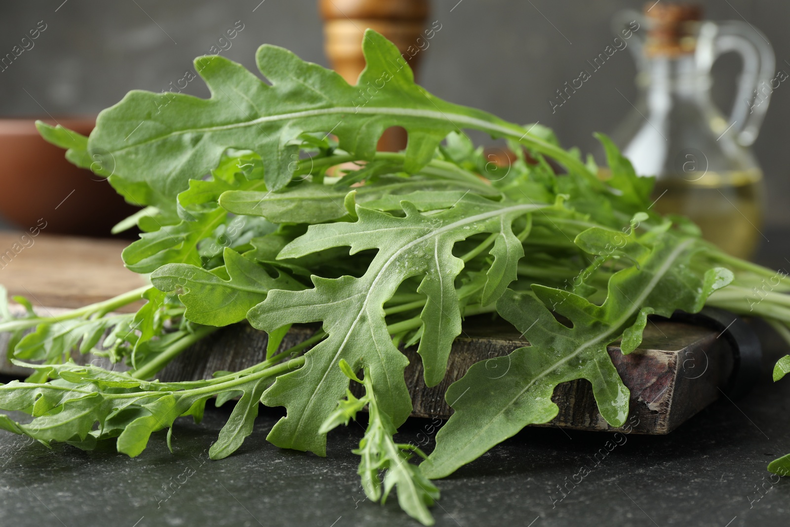 Photo of Fresh green arugula leaves on grey textured table, closeup