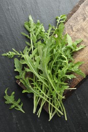 Photo of Fresh green arugula leaves on grey textured table, top view