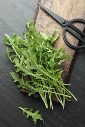 Photo of Fresh green arugula leaves and scissors on grey textured table, flat lay