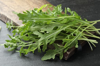 Photo of Fresh green arugula leaves on grey textured table, closeup