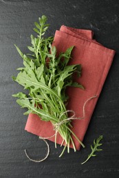 Photo of Bunch of fresh green arugula leaves on grey textured table, top view