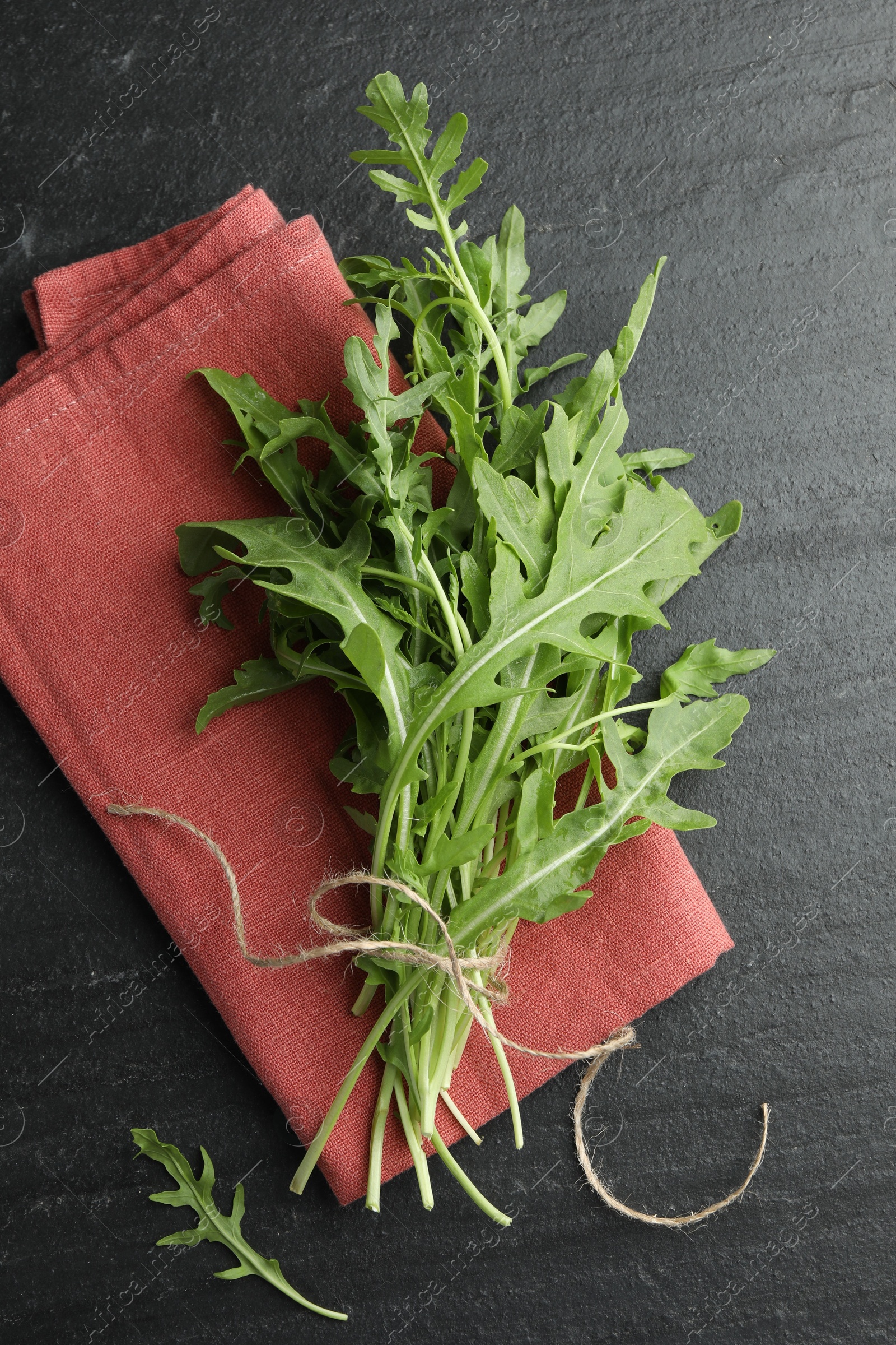 Photo of Bunch of fresh green arugula leaves on grey textured table, top view