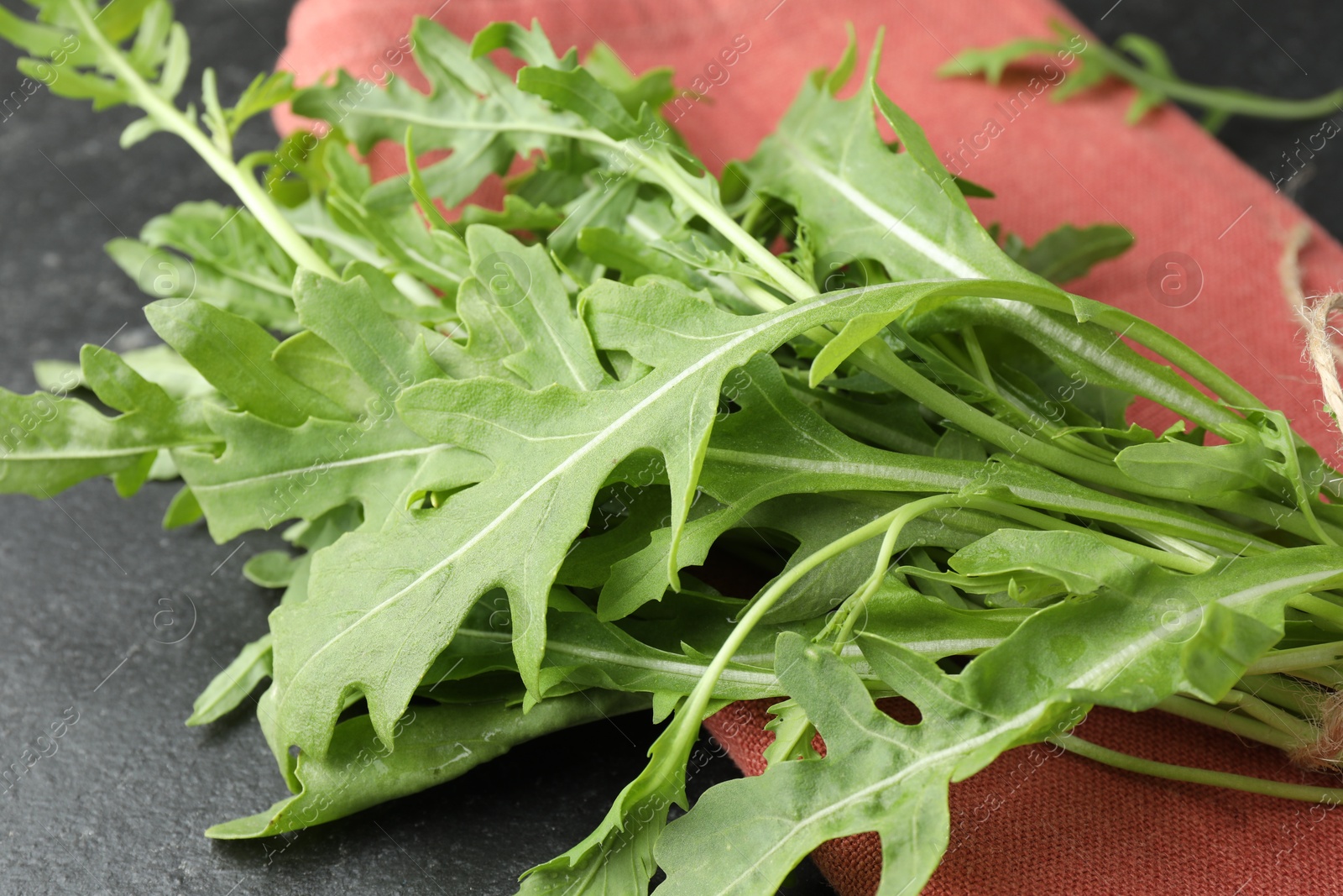 Photo of Fresh green arugula leaves on grey textured table, closeup