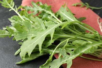 Photo of Fresh green arugula leaves on grey textured table, closeup