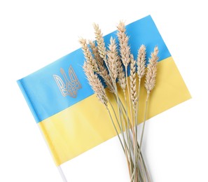 Photo of Ears of wheat and Ukrainian national flag isolated on white, top view