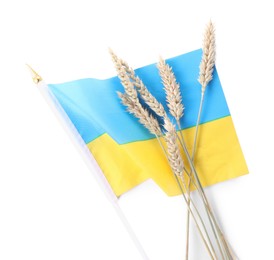 Ears of wheat and Ukrainian national flag isolated on white, top view