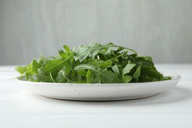 Photo of Fresh green arugula leaves on white table, closeup