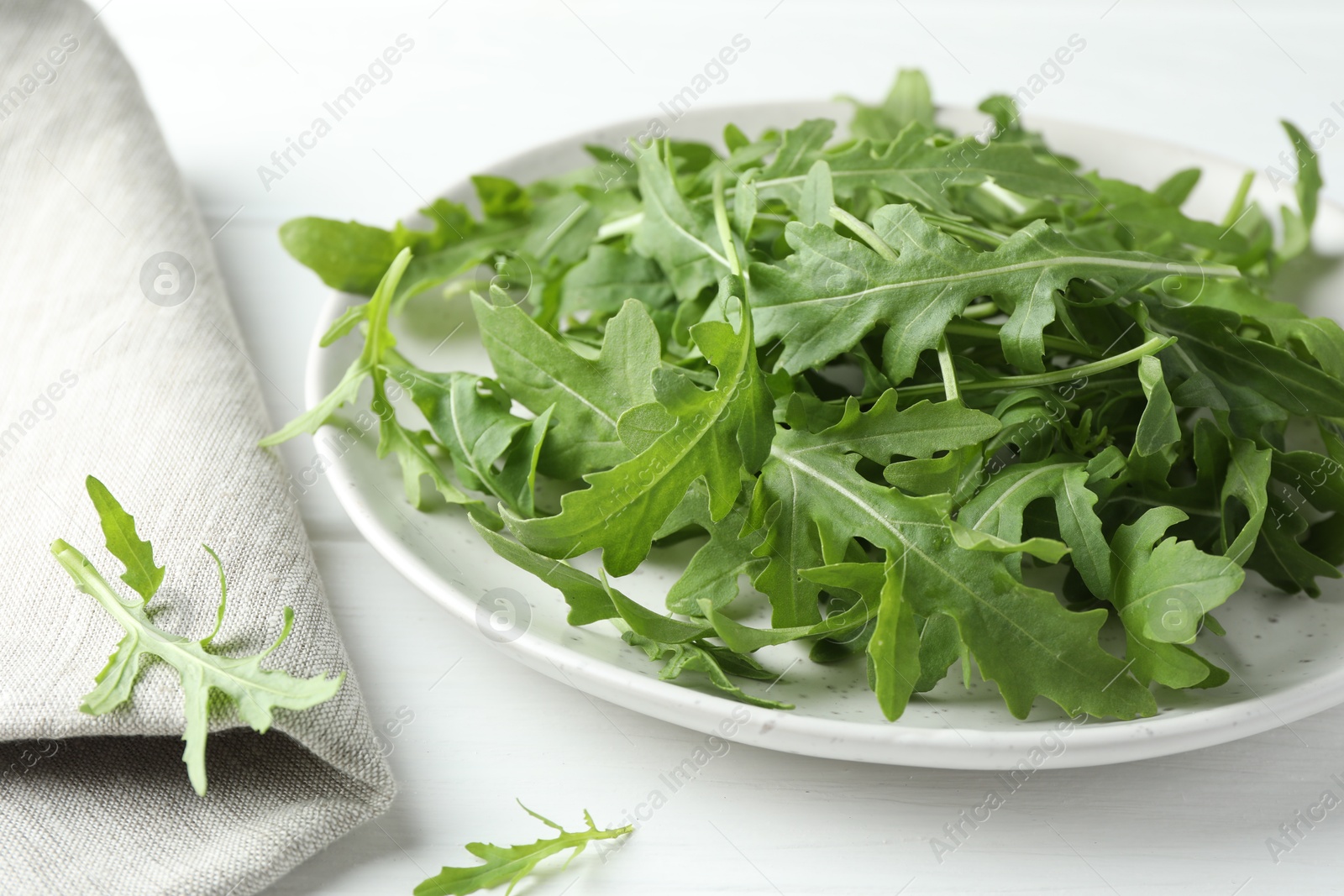 Photo of Fresh green arugula leaves on white table, closeup