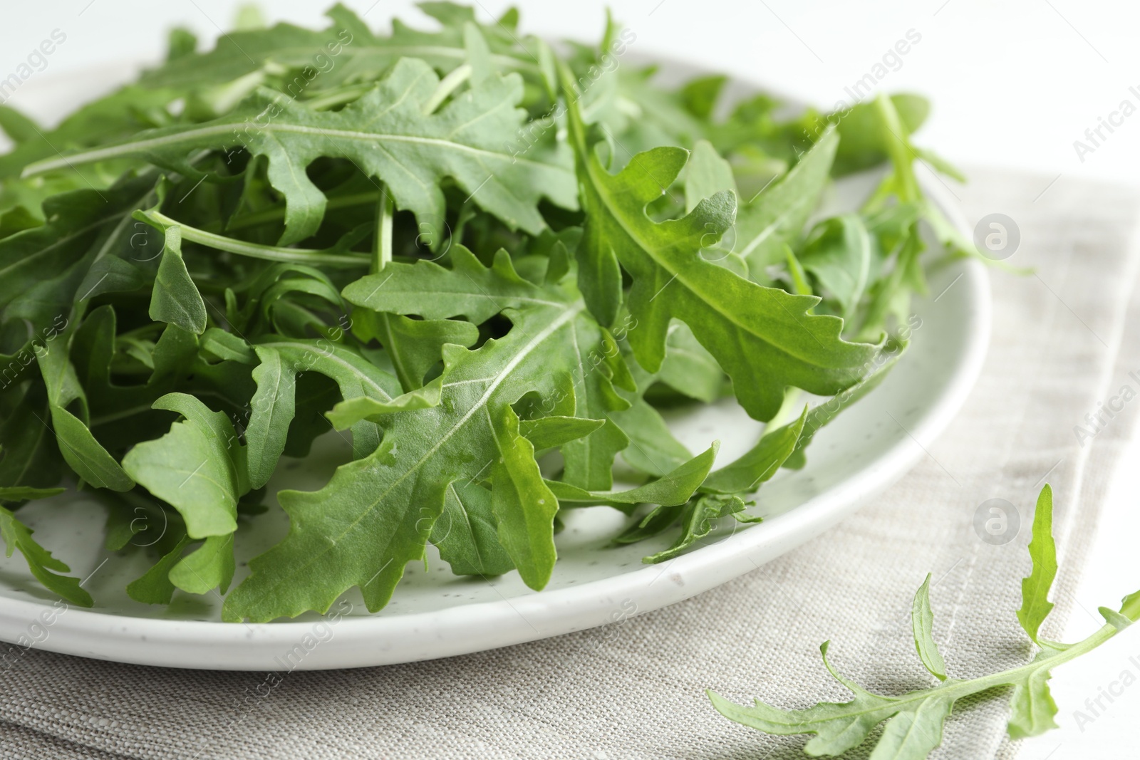 Photo of Fresh green arugula leaves on white table, closeup