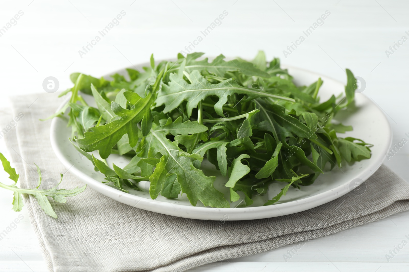 Photo of Fresh green arugula leaves on white table, closeup