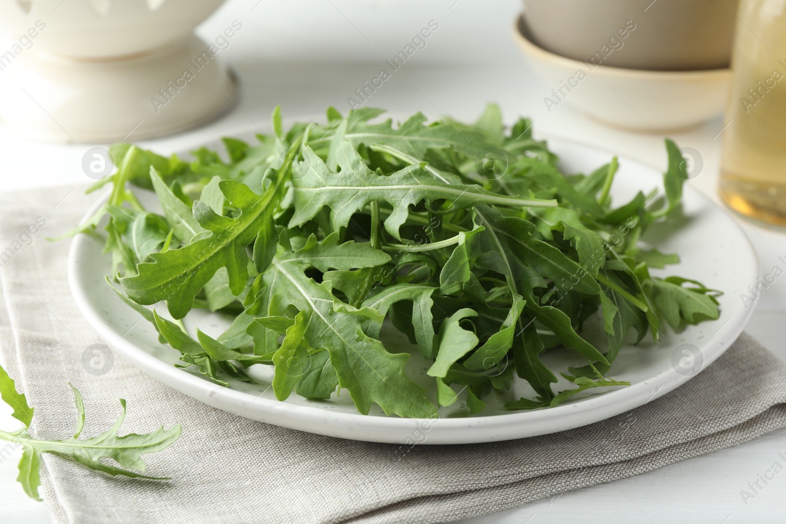 Photo of Fresh green arugula leaves on white table, closeup