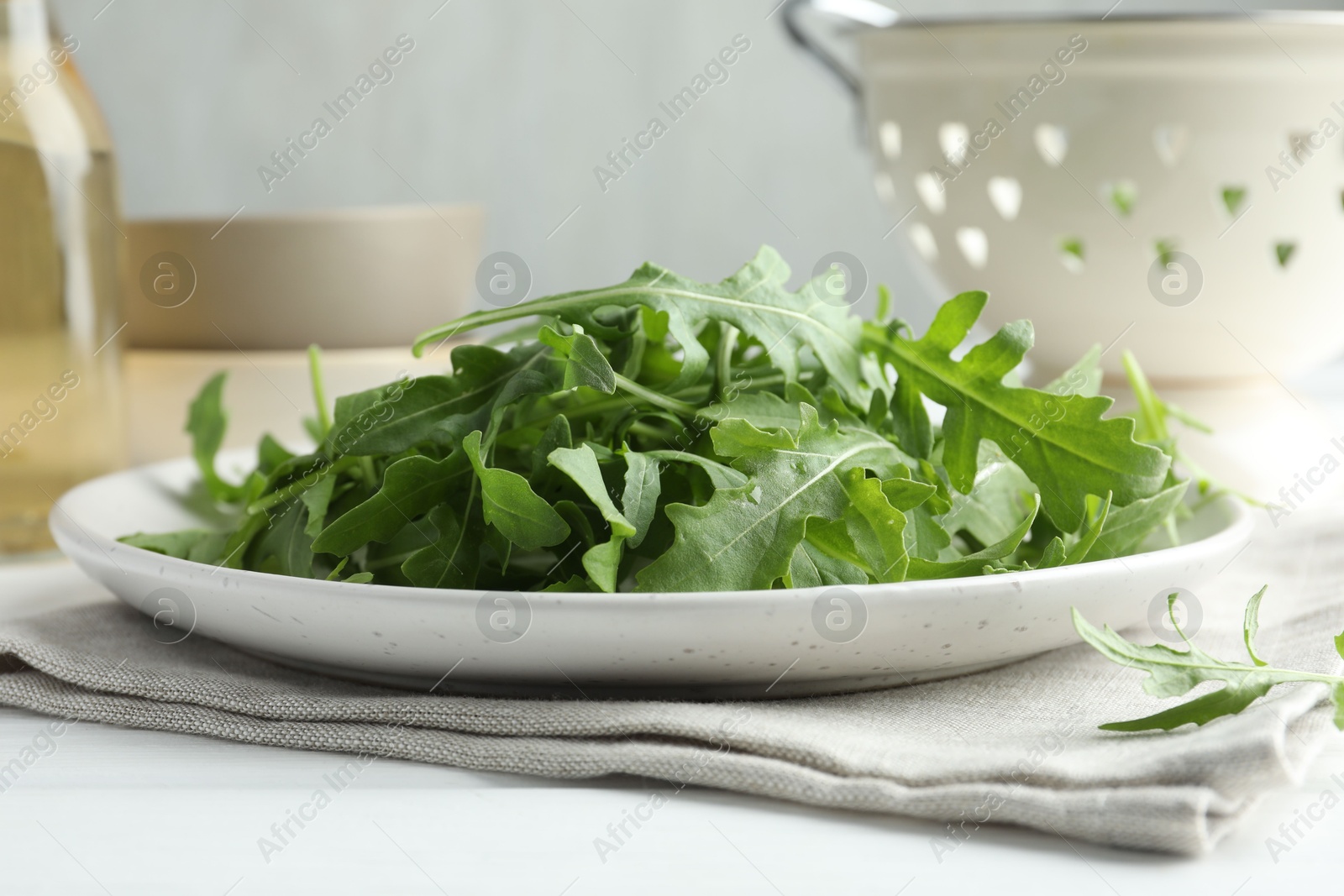 Photo of Fresh green arugula leaves on white table, closeup