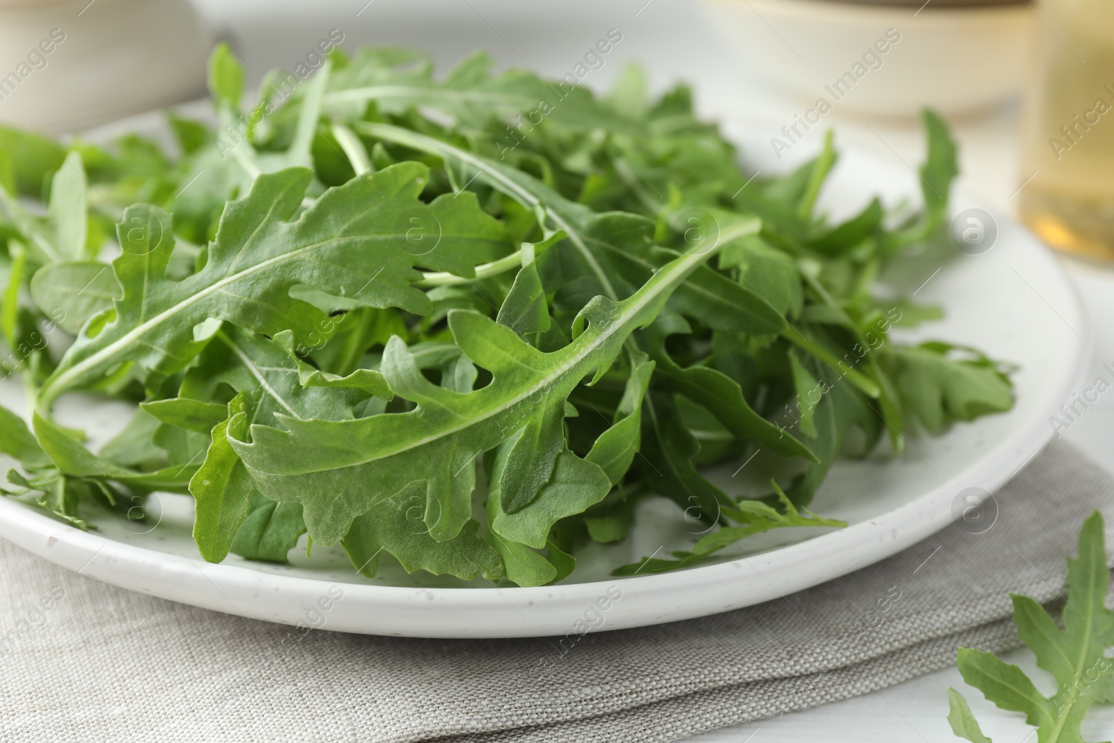 Photo of Fresh green arugula leaves on white table, closeup