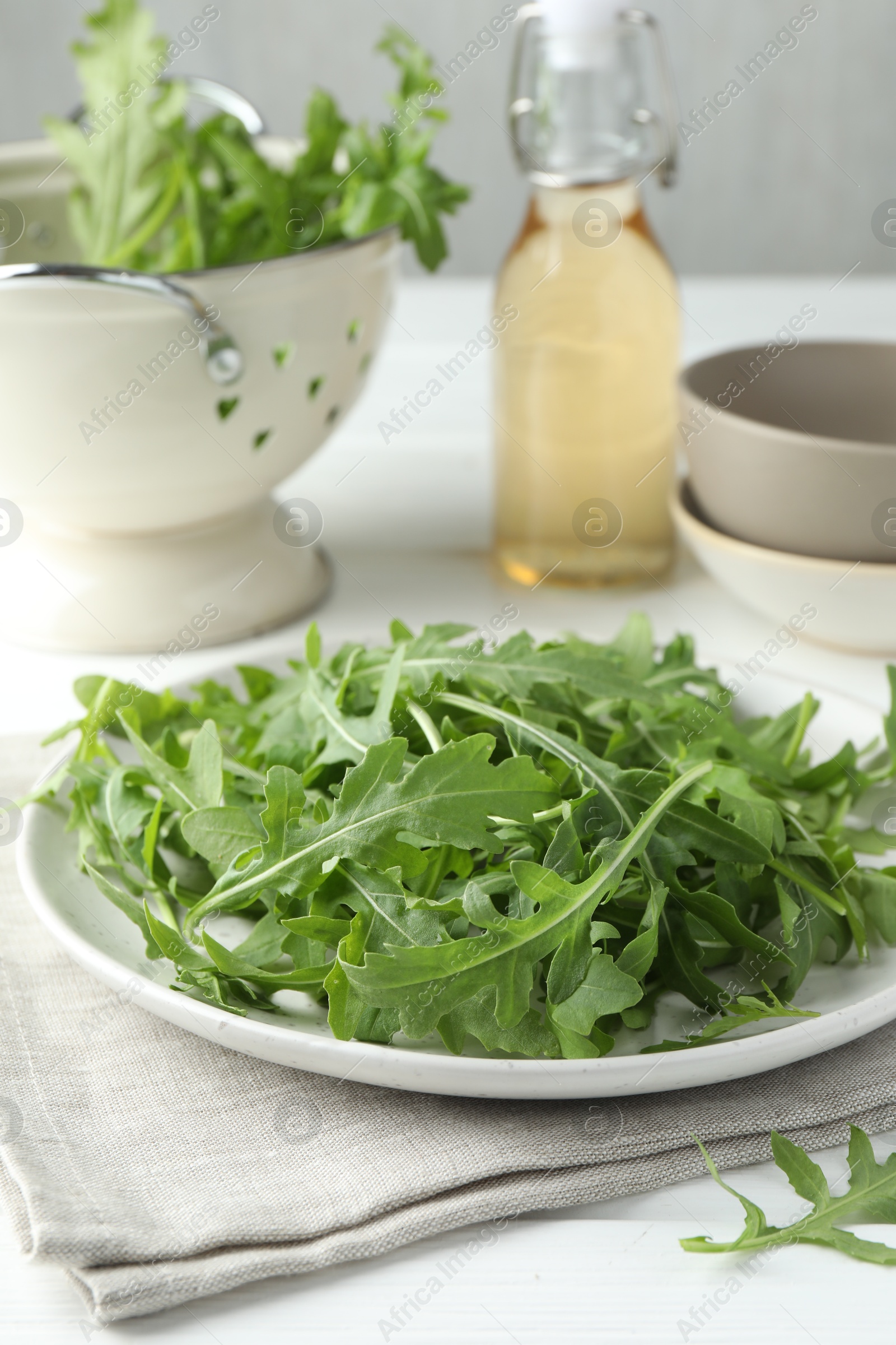 Photo of Fresh green arugula leaves on white table, closeup