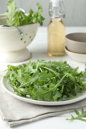 Photo of Fresh green arugula leaves on white table, closeup