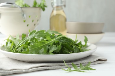 Photo of Fresh green arugula leaves on white table, closeup