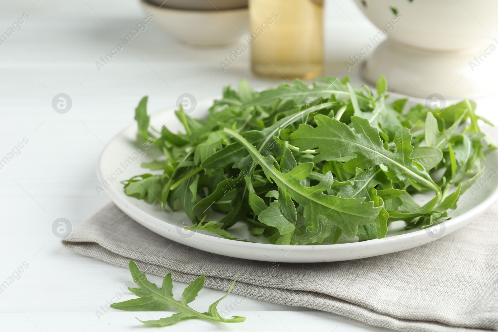 Photo of Fresh green arugula leaves on white table, closeup