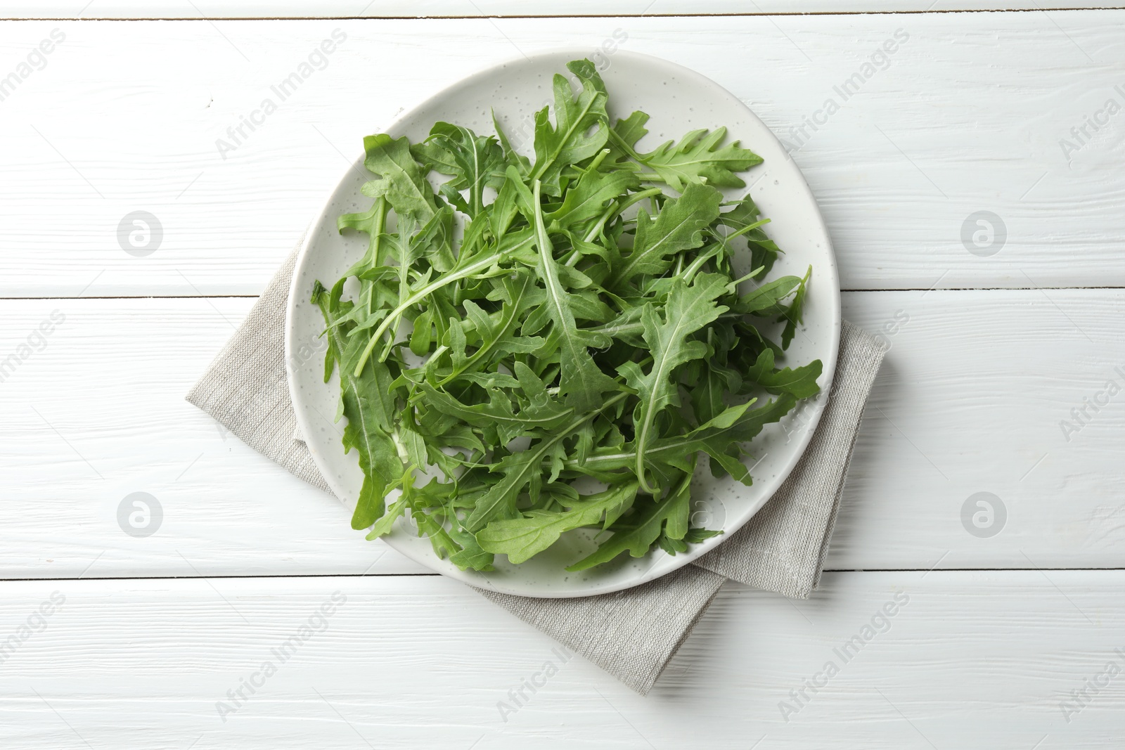 Photo of Fresh green arugula leaves on white wooden table, top view