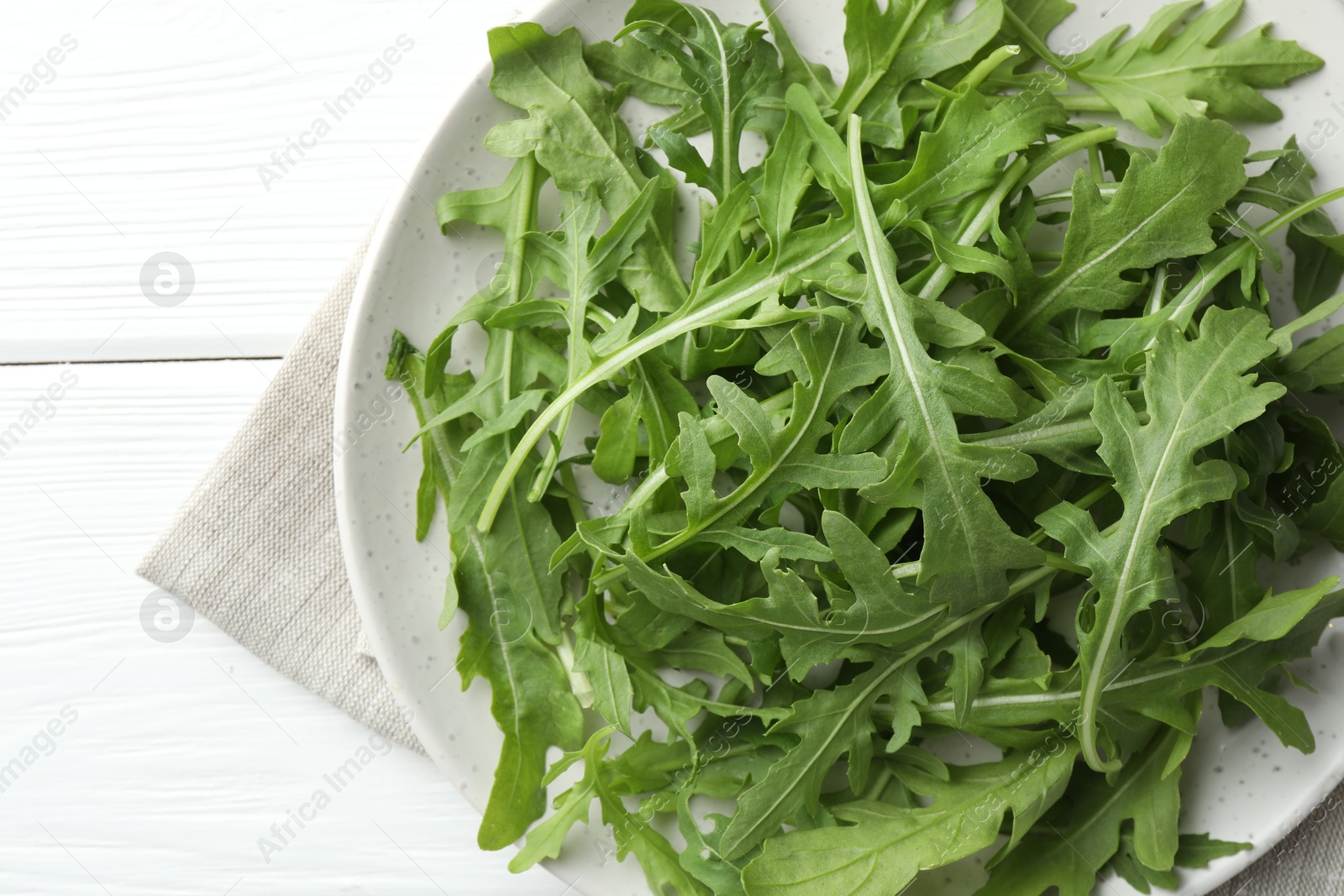 Photo of Fresh green arugula leaves on white wooden table, top view