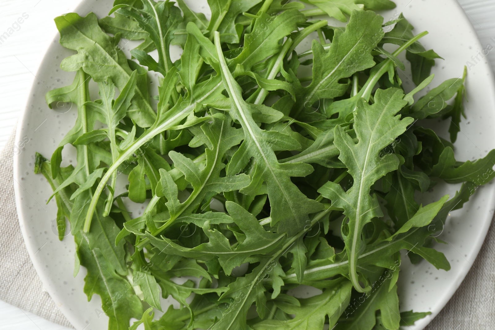 Photo of Fresh green arugula leaves on white table, top view