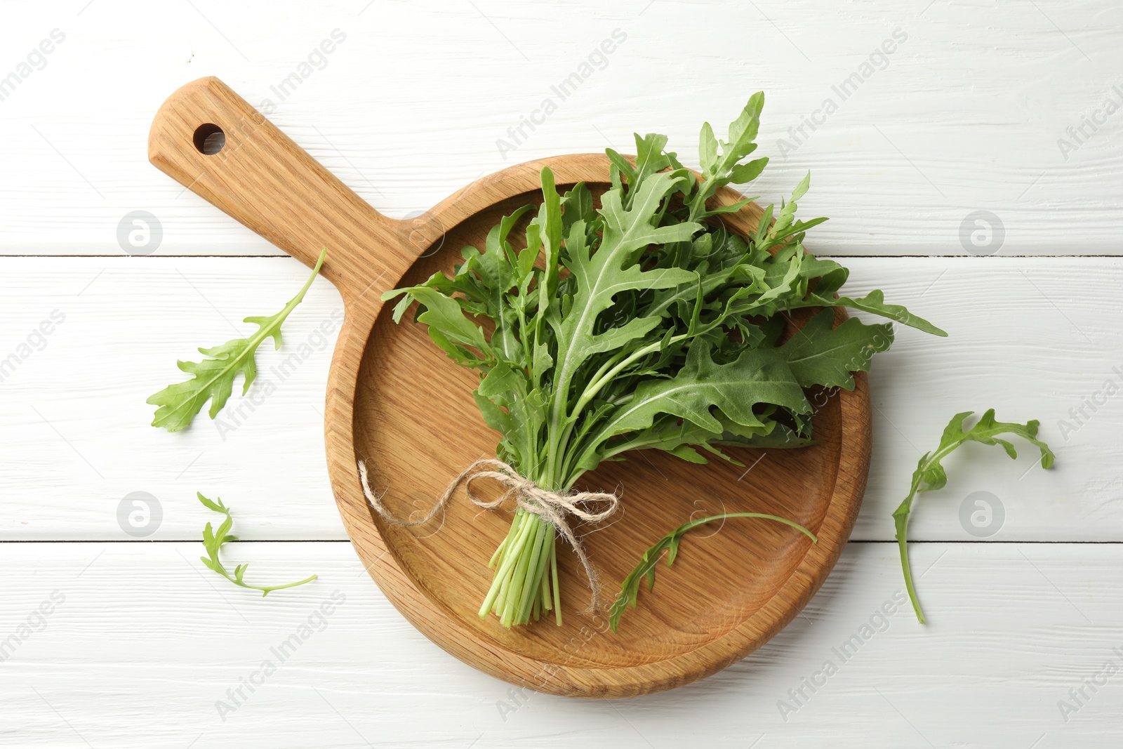 Photo of Bunch of fresh green arugula leaves on white wooden table, top view