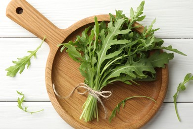 Photo of Bunch of fresh green arugula leaves on white wooden table, top view