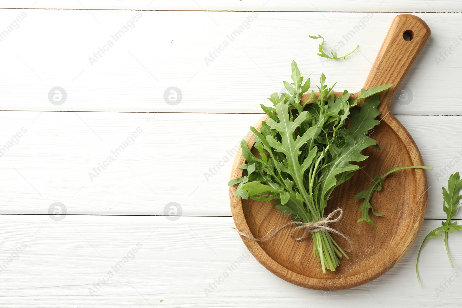 Photo of Bunch of fresh green arugula leaves on white wooden table, top view. Space for text