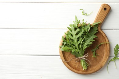 Photo of Bunch of fresh green arugula leaves on white wooden table, top view. Space for text